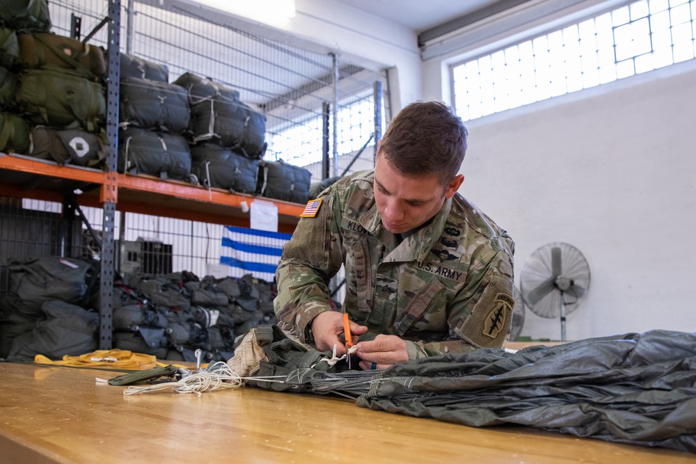 Parachute riggers inspecting and packing parachutes in a rigging facility