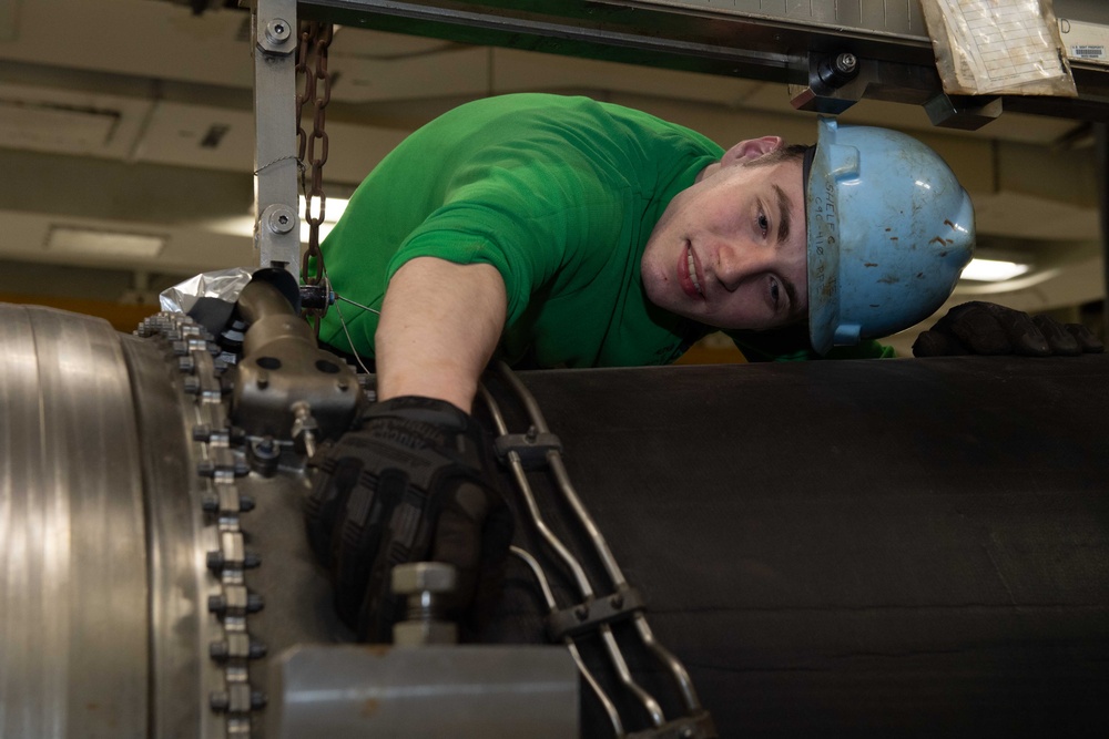 Aviation technician performing maintenance on a jet engine aboard an aircraft carrier