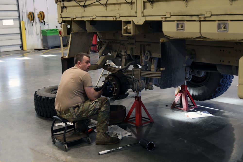 U.S. Army soldiers performing maintenance on military vehicles in a maintenance facility
