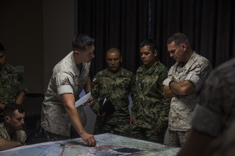 U.S. Marines and partner nation military personnel review a tactical map