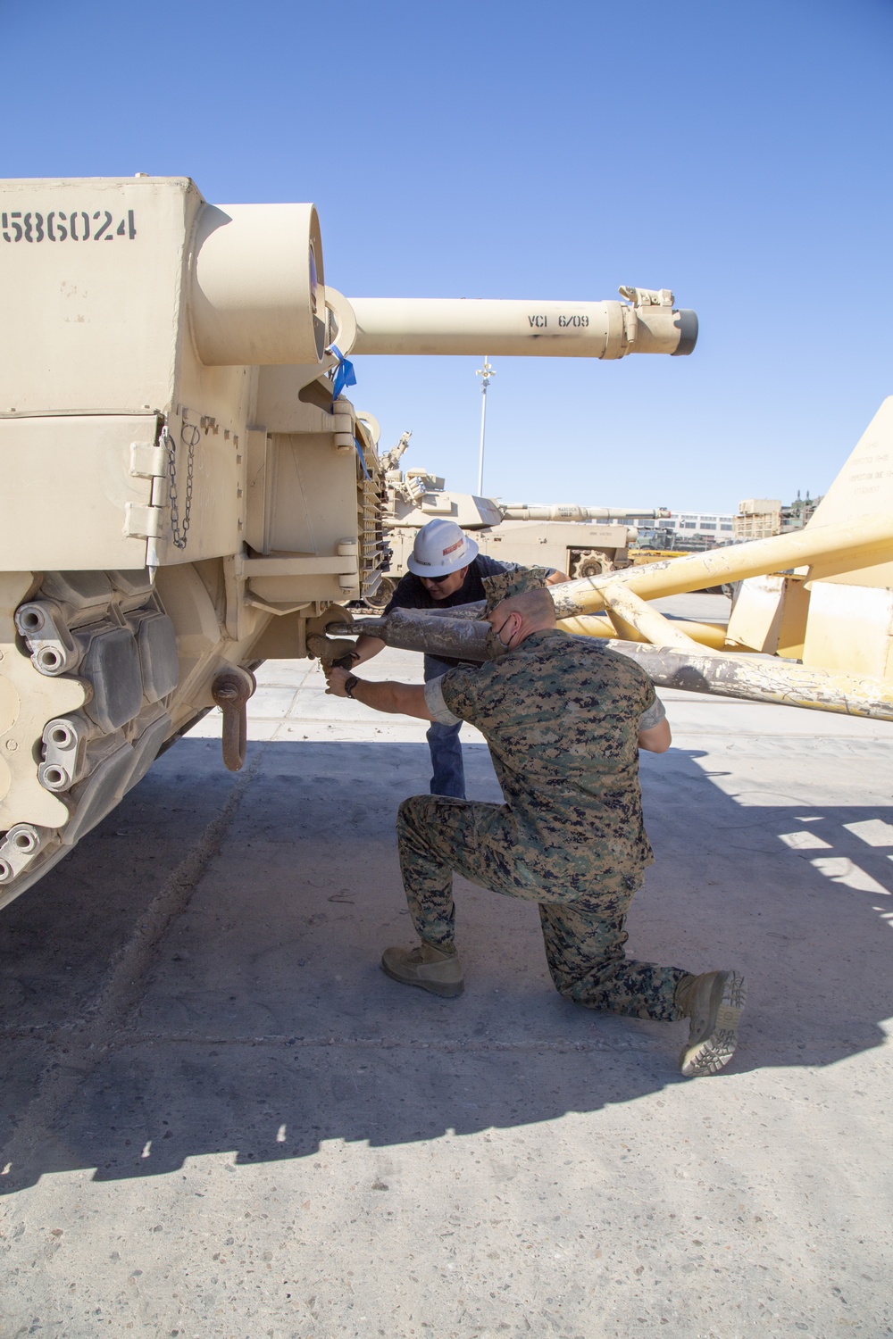 A Caterpillar tractor positions a divested M1A1 Abrams tank at a storage facility
