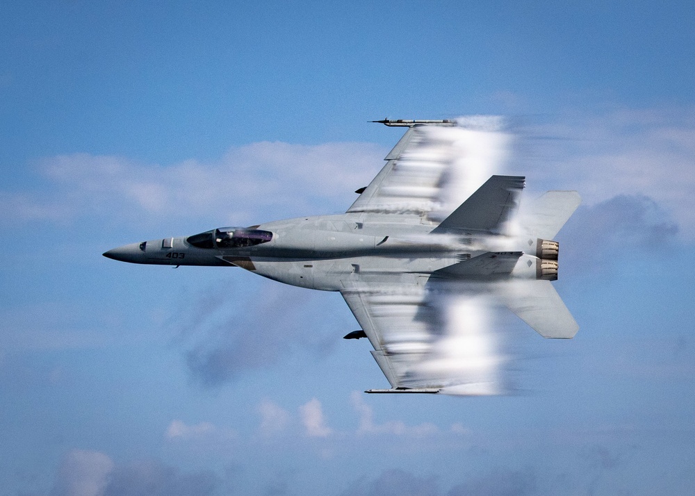 F/A-18E Super Hornet conducting a supersonic pass with visible vapor cone